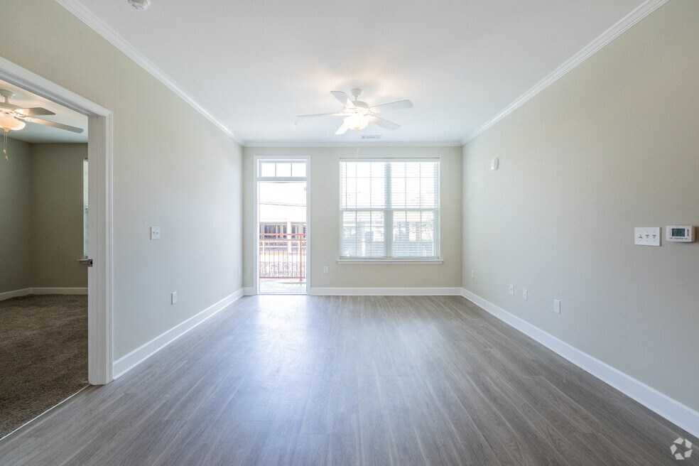 an empty living room with a ceiling fan and a window