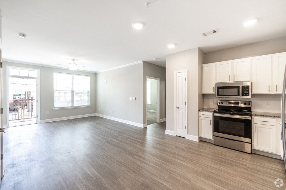 an empty kitchen and living room with a stove and microwave
