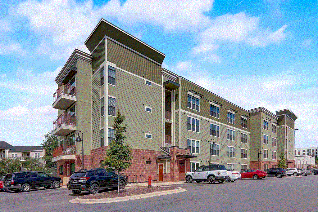 a large a[artment building with cars parked in a parking lot