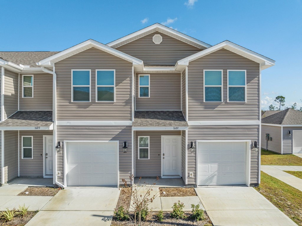 a beige and brown house with two garage doors