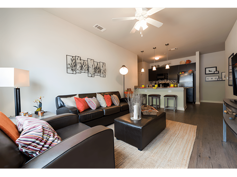 a living room with leather furniture and a kitchen in the background