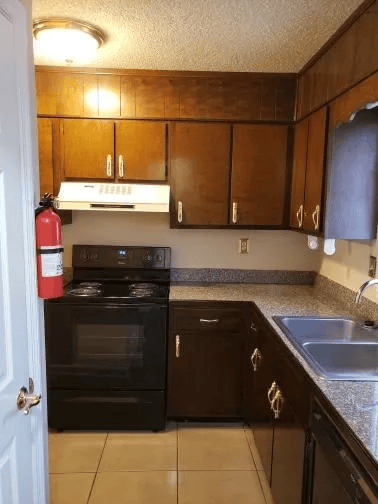 A kitchen with a black oven and brown cabinets.