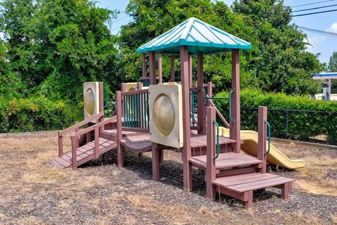 A playground with a green roof and a yellow slide.