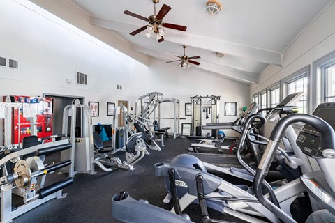 A gym with a variety of equipment including treadmills, weights, and exercise machines.