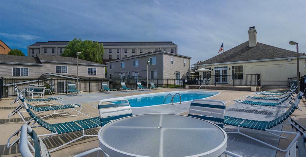 a swimming pool with chairs and tables around it