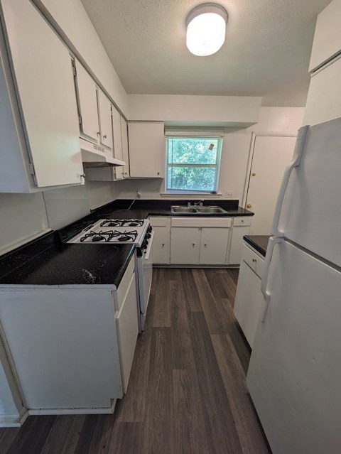 A kitchen with white cabinets and a black countertop.