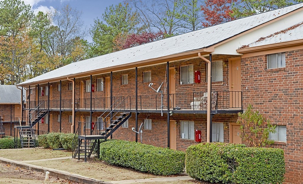 A red brick building with a white roof and a balcony with a railing.