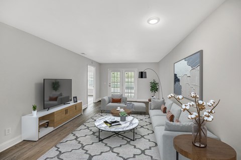 A living room with a grey couch, a coffee table, a television, and a painting on the wall.