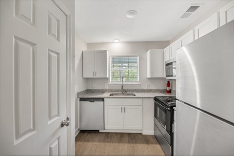 A kitchen with white cabinets and a black dishwasher.