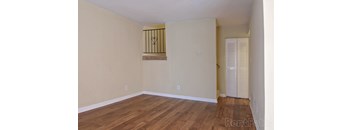 A room with wooden floors and a window with bars on it.