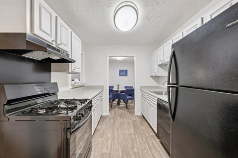 A black refrigerator is in the foreground of a kitchen.
