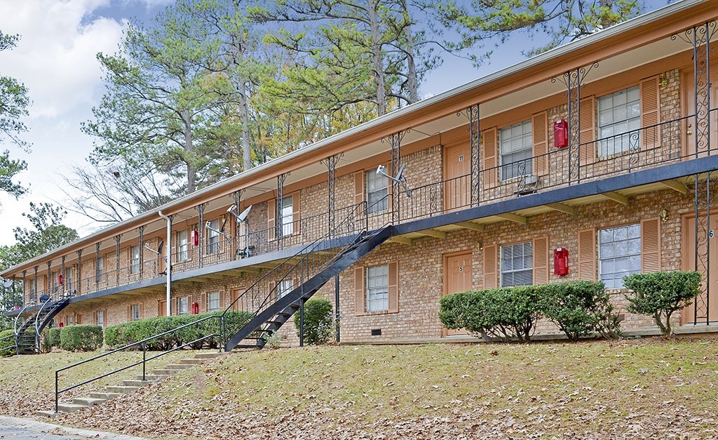 A red fire hydrant is on the balcony of a brick apartment building.