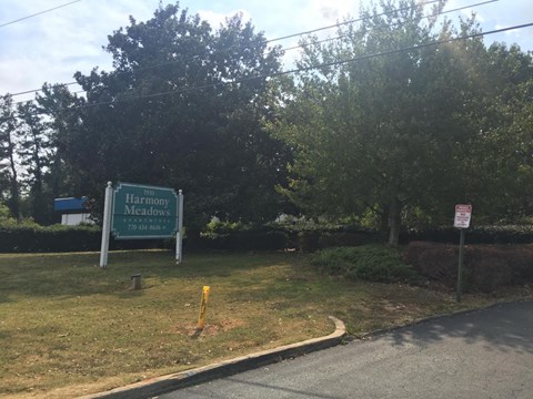A sign for Harmony Meadows is displayed in front of a grassy area.