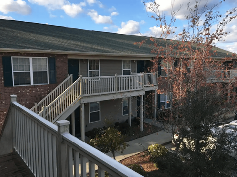 A house with a balcony and a tree in front.