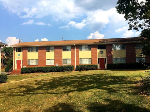 A red and yellow building with a green lawn in front.