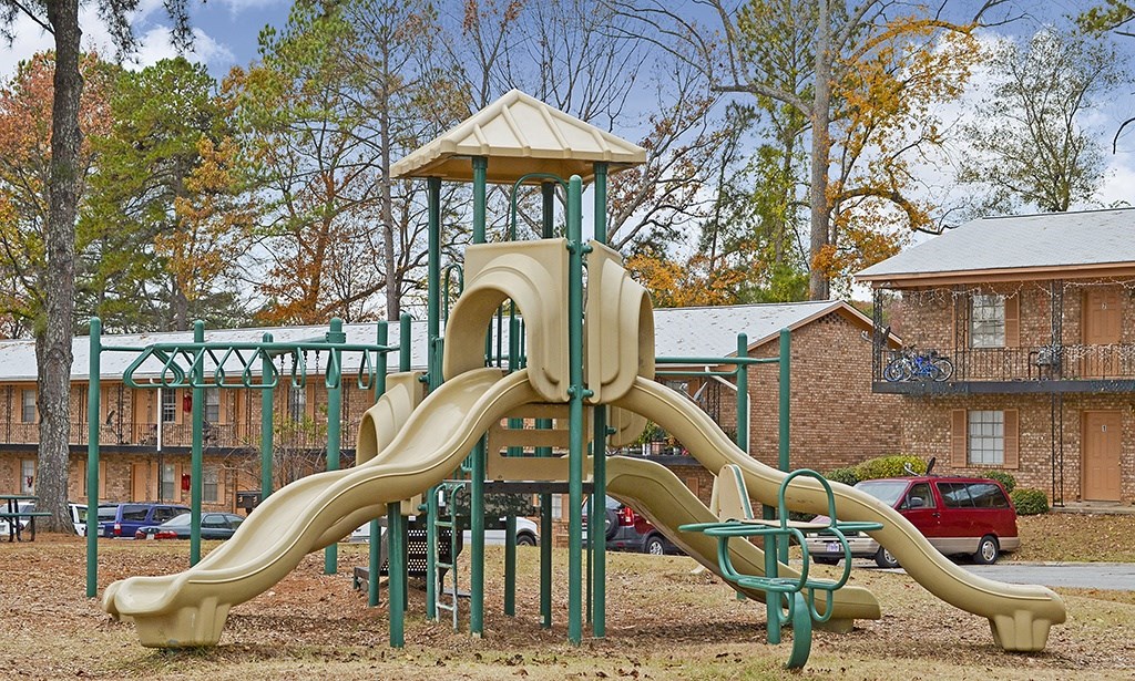 A playground with a yellow slide and a green railing.