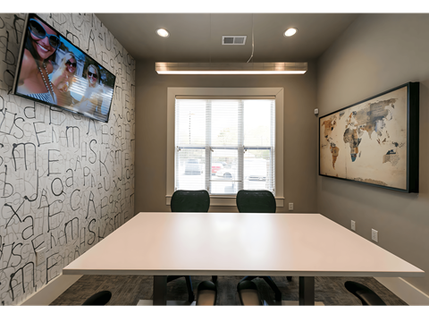 a conference room with a white table and chairs and a monitor on the wall