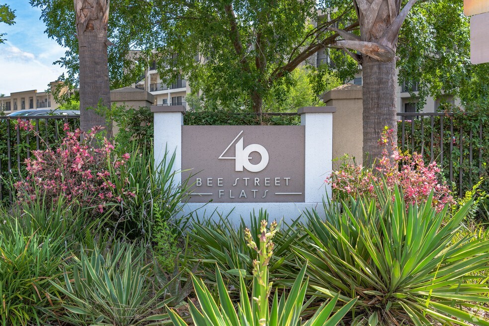 a sign in front of a building with trees and plants