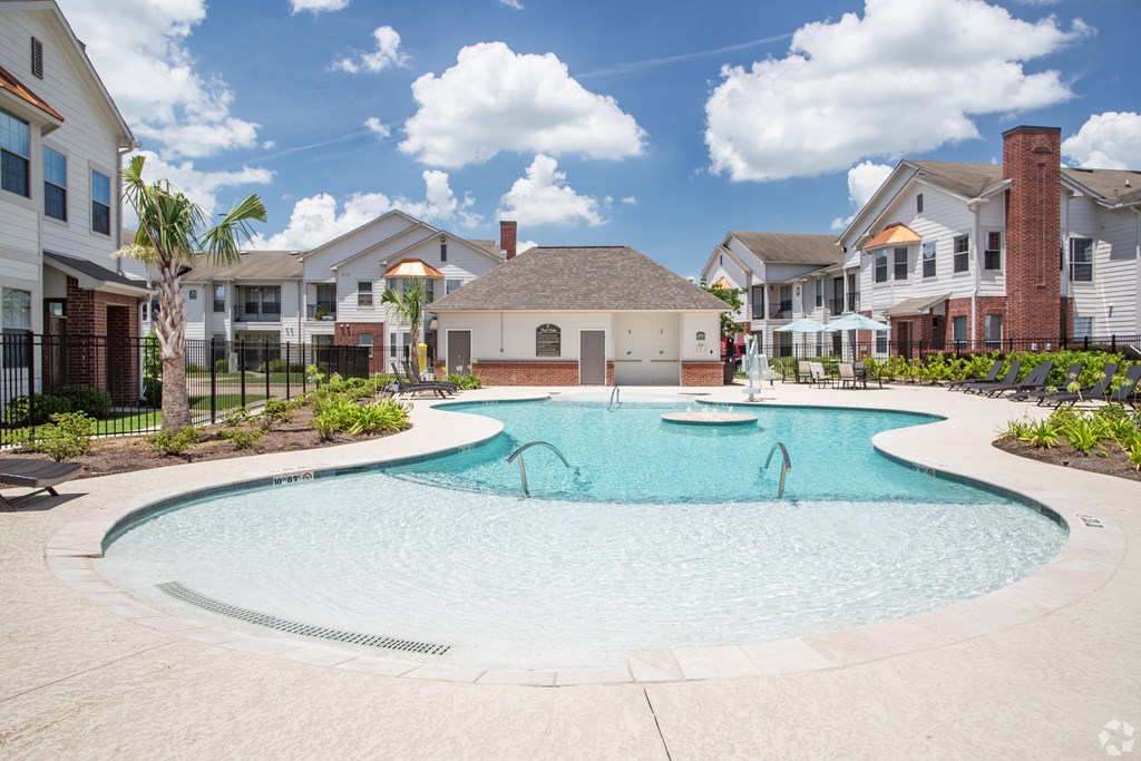 A swimming pool surrounded by houses and palm trees.