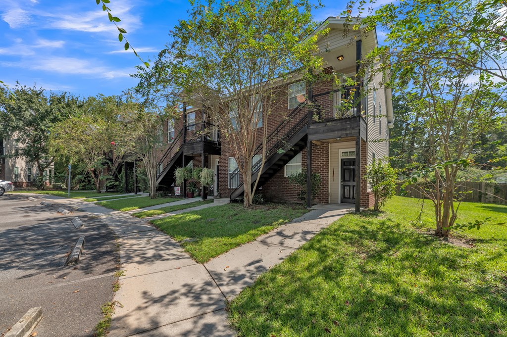 a brick apartment building with stairs on the side of a sidewalk