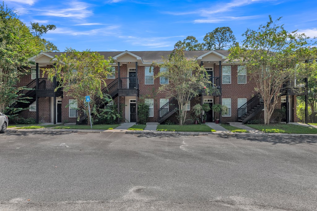 an apartment building with a parking lot and trees