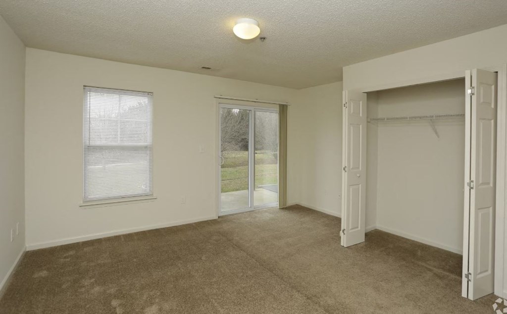 an empty bedroom with a door to a walk in closet
