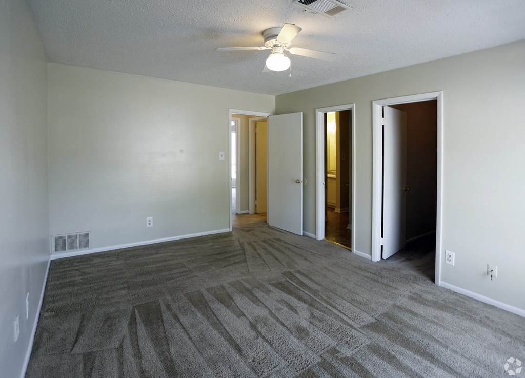 an empty living room with carpet and a ceiling fan