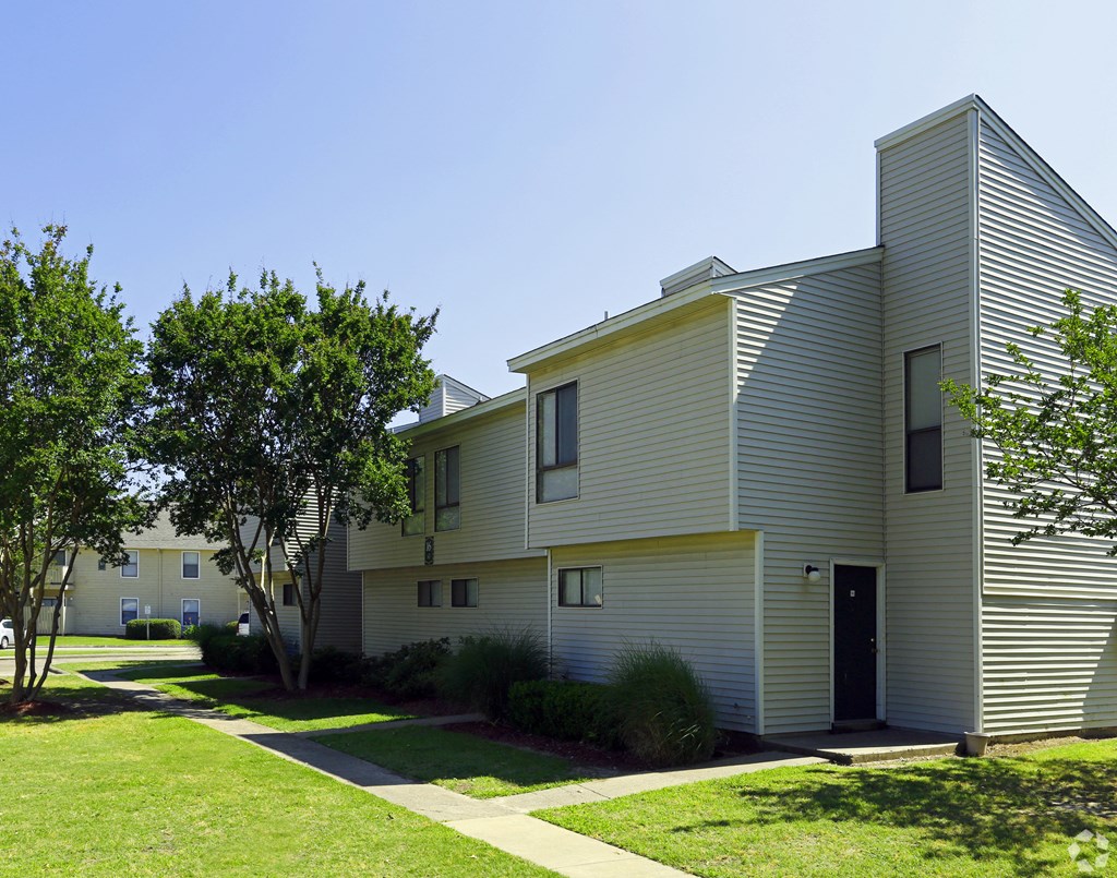 an exterior view of an apartment building with a sidewalk and grass