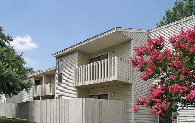 a white house with a balcony and pink flowers