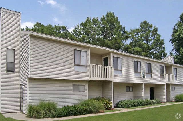 a white apartment building with a balcony and grass