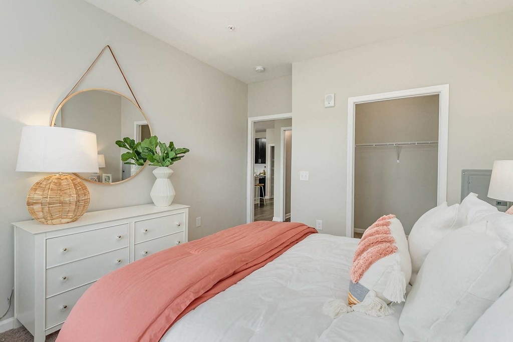 a bedroom with a large bed and a dresser with a mirror