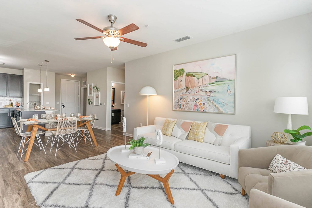 a living room with a white couch and a coffee table in front of a dining room table