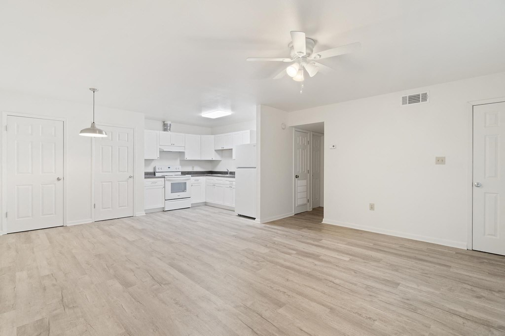 a spacious living room with white walls and hardwood floors