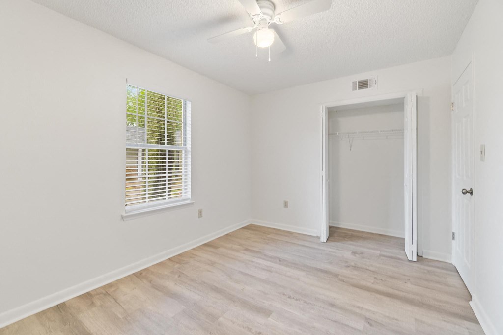 a bedroom with hardwood floors and white walls