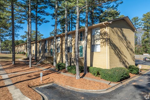 A building with a yellow siding and a green bush in front.