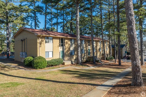 A small building with a red roof is surrounded by trees.