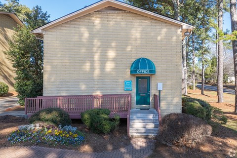 A small yellow building with a green awning and a sign that says "OFFICE" on it.