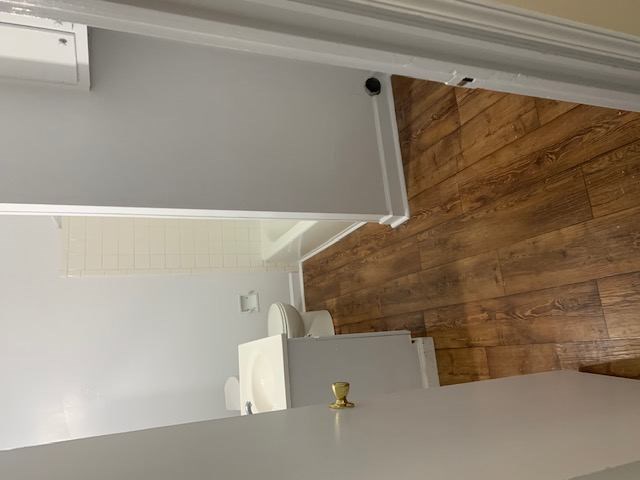 A white cabinet with a gold handle is mounted on a wall with wooden planks.
