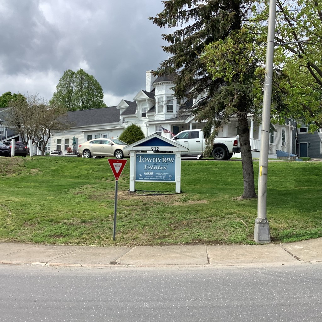 a sign on the side of a lawn in front of a house