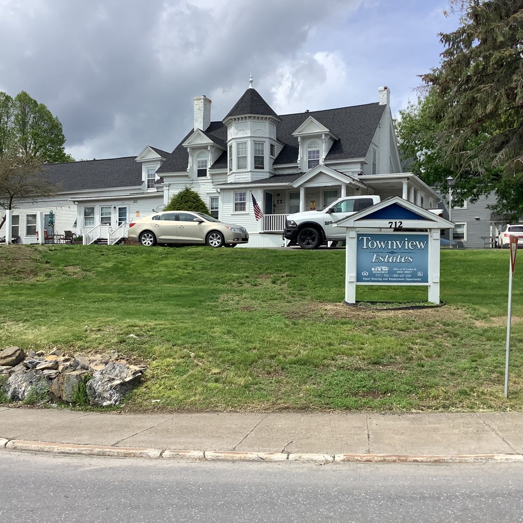 a large white house on a lawn with a sign for town view apartments