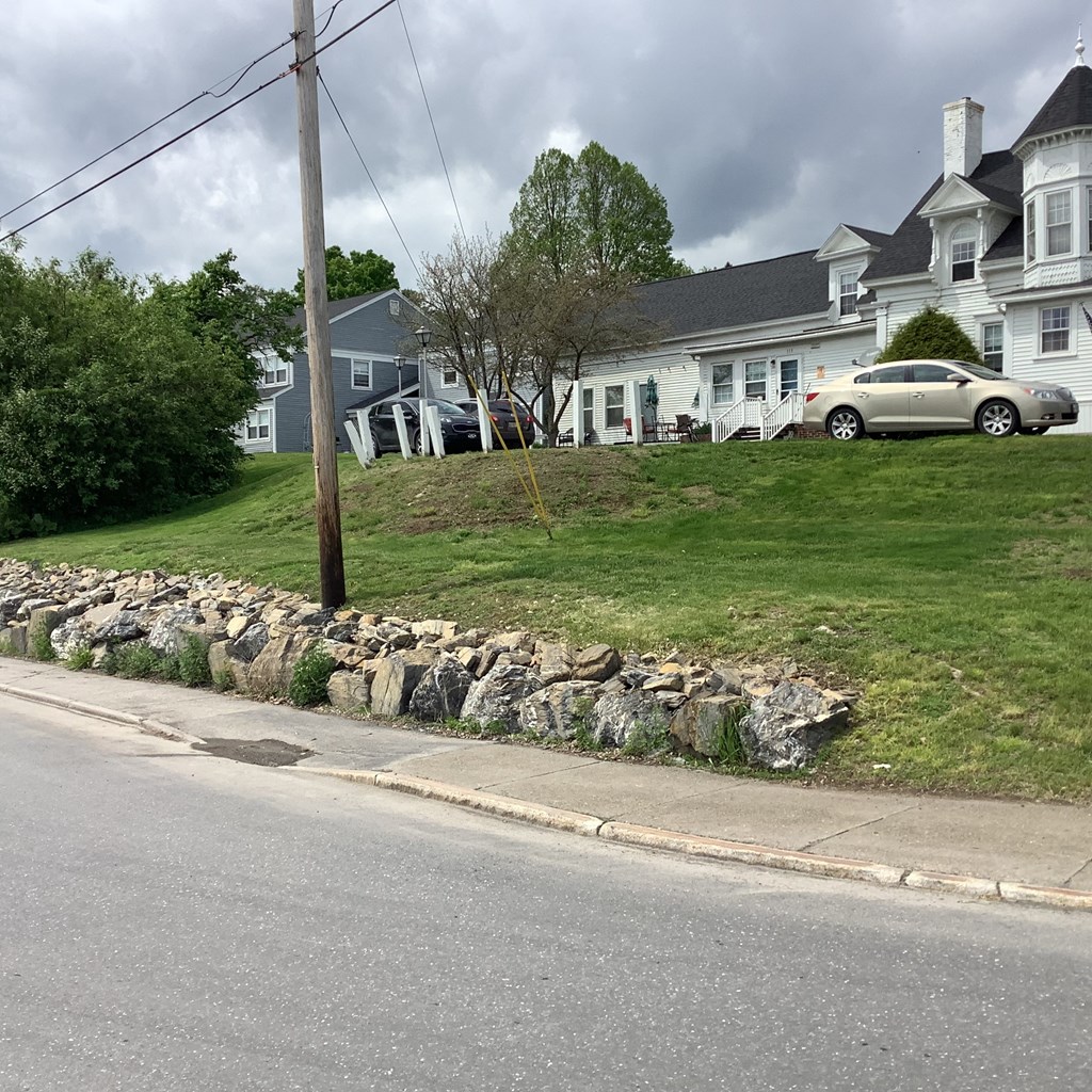 a stone retaining wall on a hill in front of a house