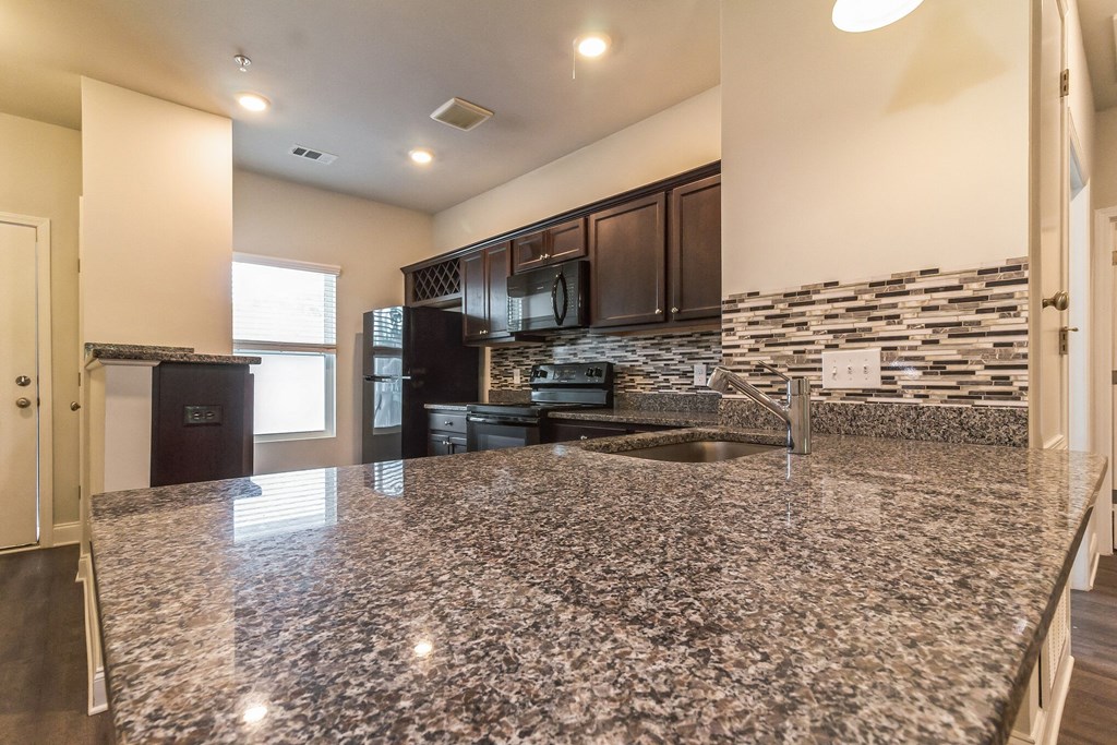 a kitchen with granite countertops and dark wood cabinets