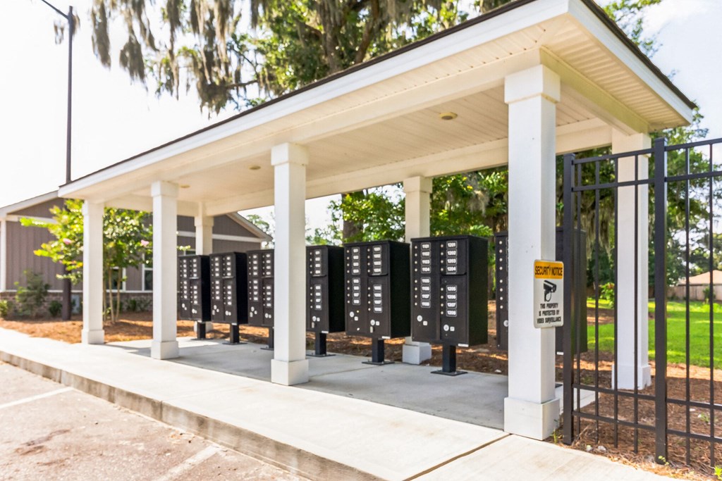 a row of black voting booths under a pavilion with trees in the background