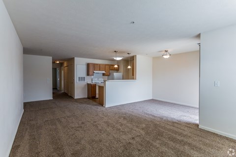 A spacious living room with a kitchen in the background.