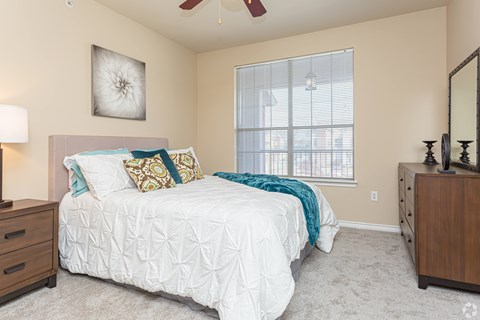 A bedroom with a white bed and a ceiling fan.