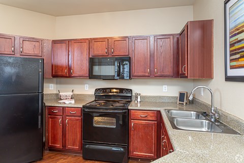 A kitchen with brown cabinets and black appliances.