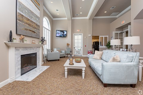 A living room with a fireplace, a couch, a chair, a coffee table, and a painting on the wall.