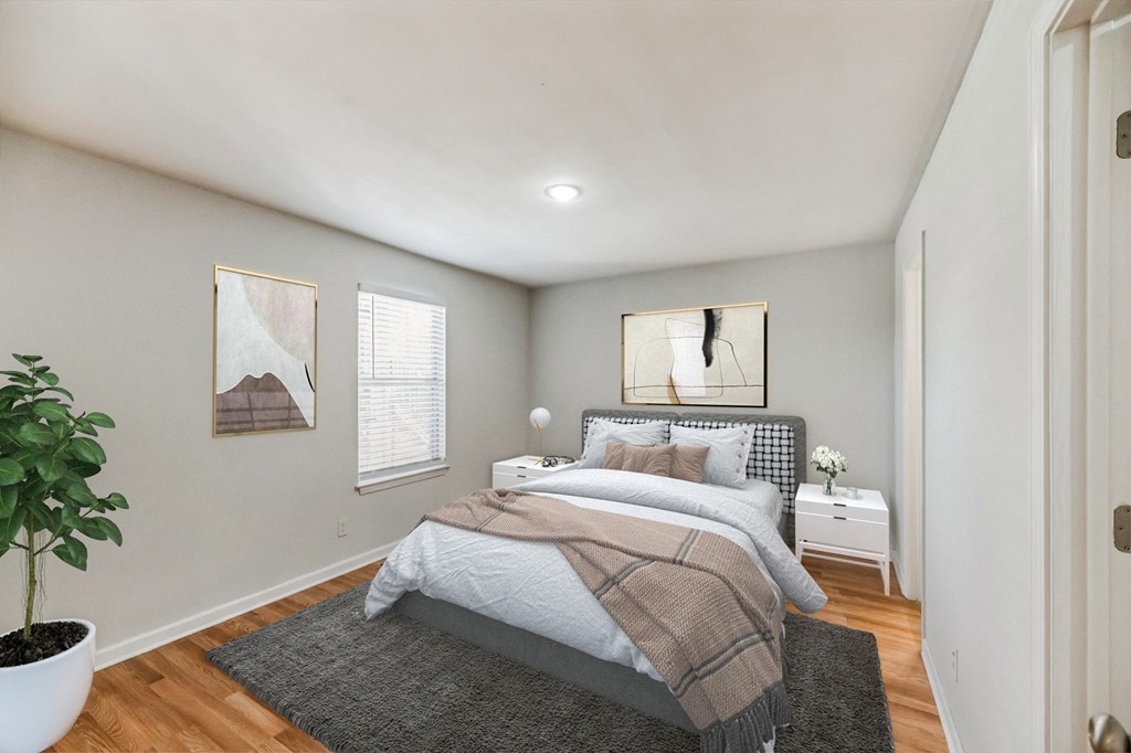 a bedroom with white walls and wood floors and a bed