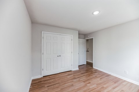 A room with a white door and wooden flooring.