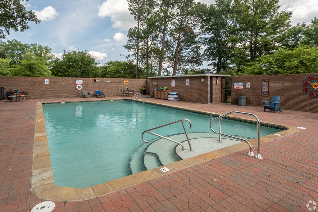 a swimming pool with a brick wall and a fence around it